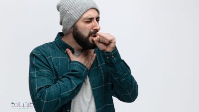 unhealthy young man wearing winter hat keeping hand chest fist front mouth coughing with closed eyes isolated white background with copy space scaled