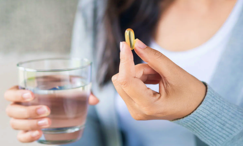 woman holding pill supplement glass water.webp